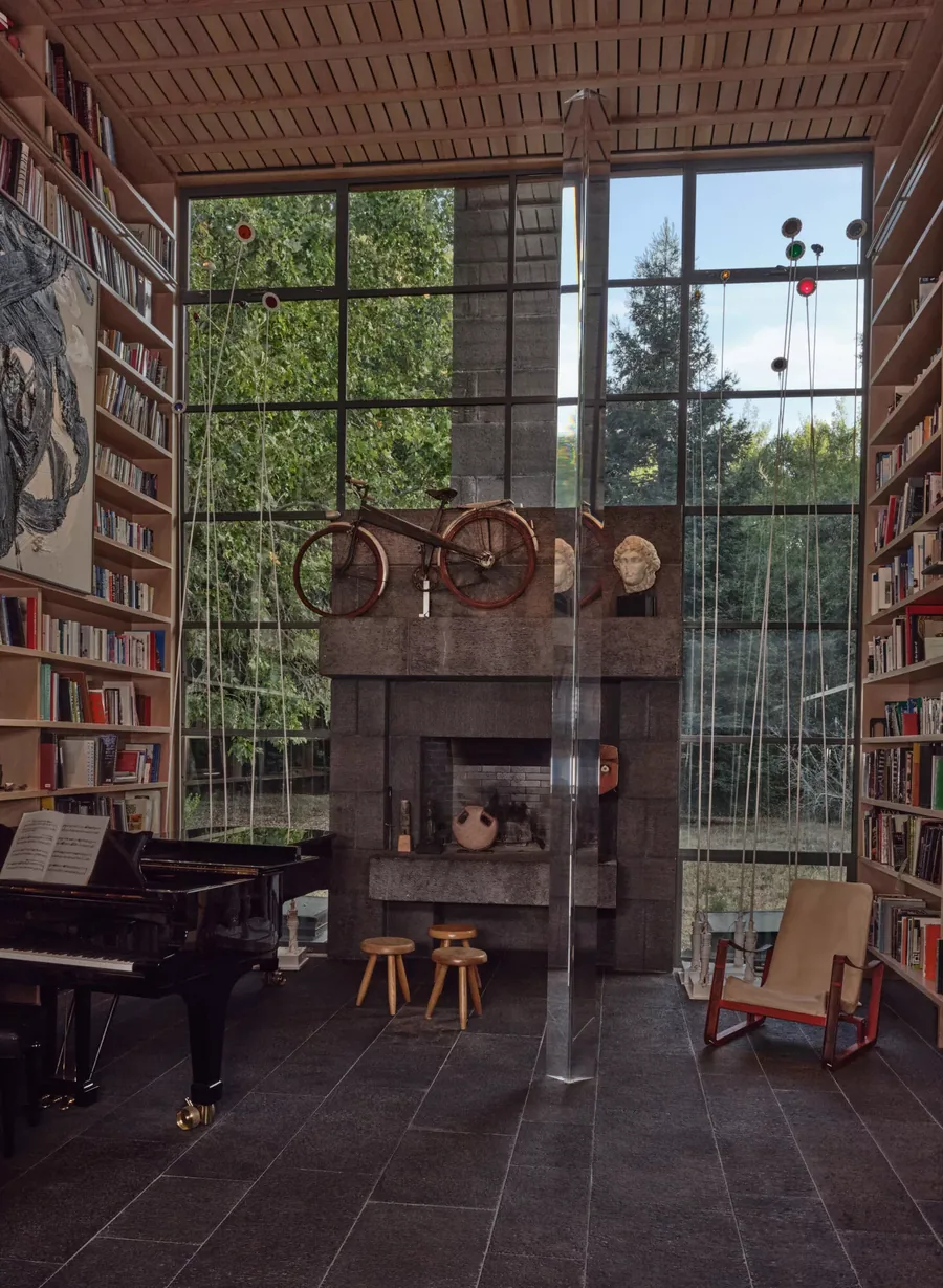 Christie's, Anthology of Design: biblioteca con piano de cola, chimenea de piedra y una bicicleta sobre la repisa
