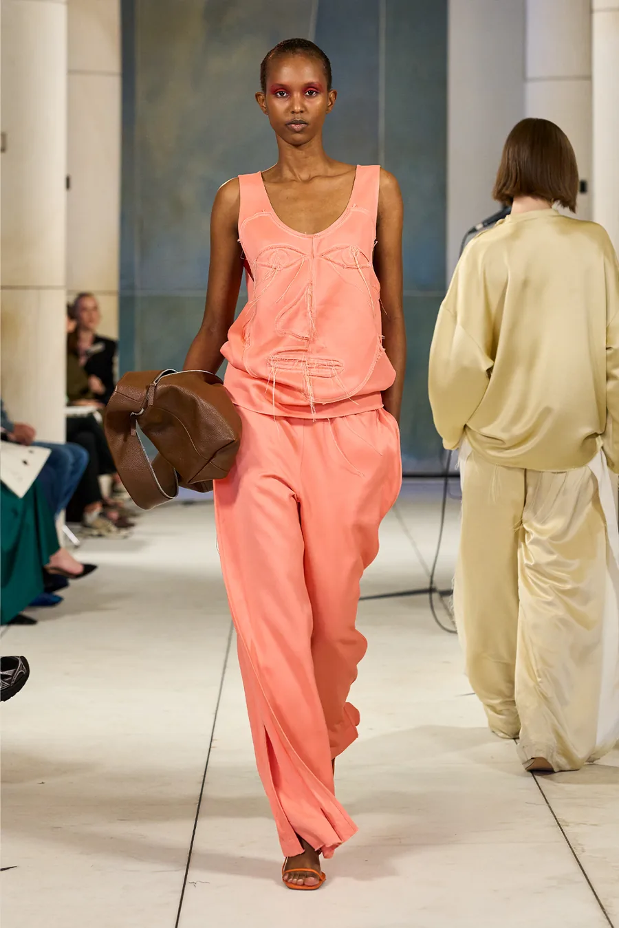 SHOWstudio, Litkovska S/S 27 STRICHA: modelo con top coral y pantalón ancho coral, con un bolso de piel marrón