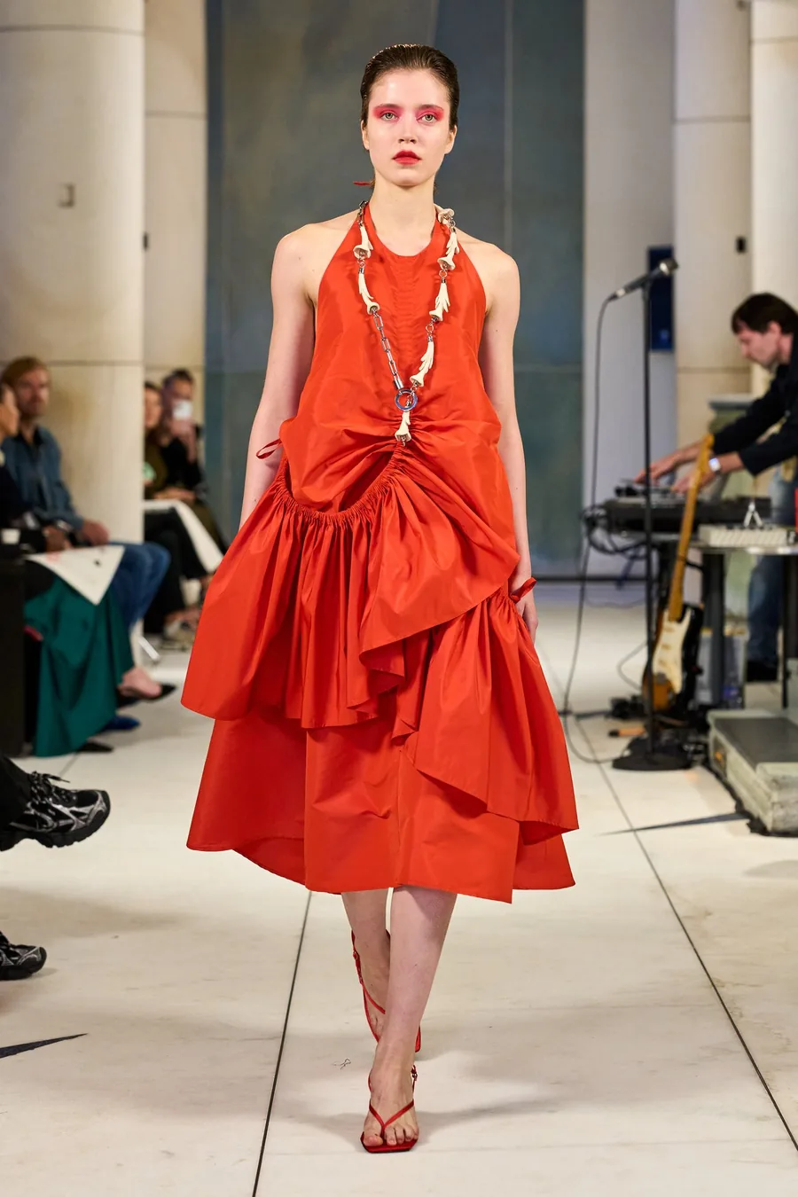 SHOWstudio, Litkovska S/S 27 STRICHA: una modelo con un vestido rojo de cuello halter con volantes y un collar largo en la pasarela